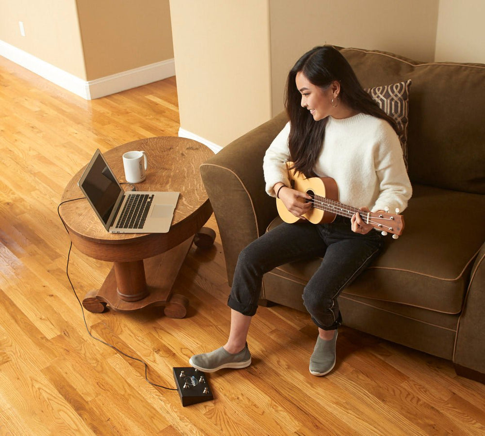 
                  
                    A young girl is learning Ukulele online  by looping and slowing down sections of the video without taking her hands off her instrument, saving time and without being frustrated.  Her foot is on the Vidami YouTube looper which is  connected to a laptop computer via USB cable.
                  
                